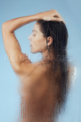Buy stock photo Studio shot of an attractive young woman taking a shower against a blue background