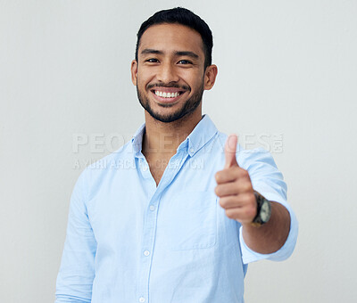 Buy stock photo Portrait of a confident young businessman showing thumbs up against a white background