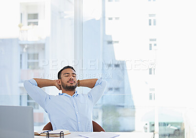 Buy stock photo Shot of a young businessman sitting with his hands behind his head at his desk in an office