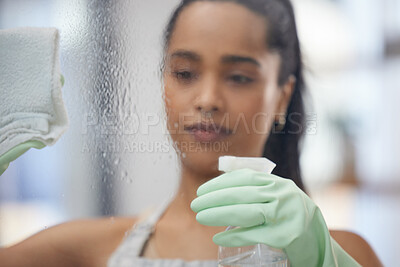 Buy stock photo Shot of a young woman cleaning windows at home