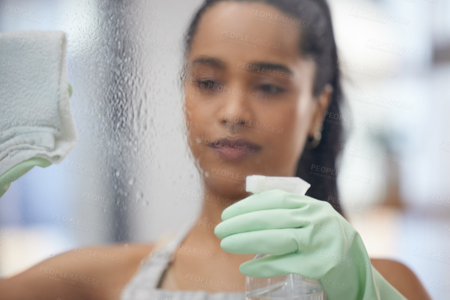 Buy stock photo Shot of a young woman cleaning windows at home