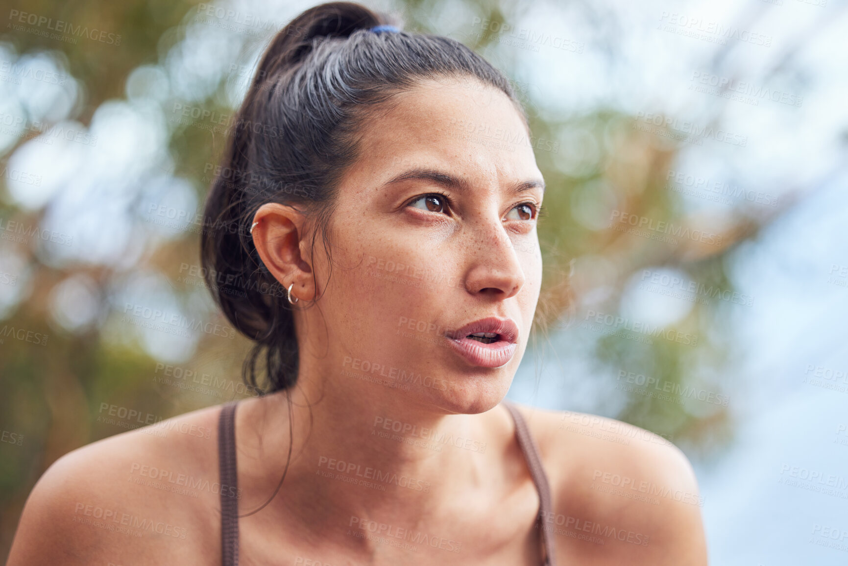 Buy stock photo Shot of a sporty young woman taking a break while exercising outdoors