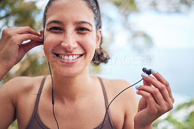 Buy stock photo Portrait of a sporty young woman wearing earphones while exercising outdoors