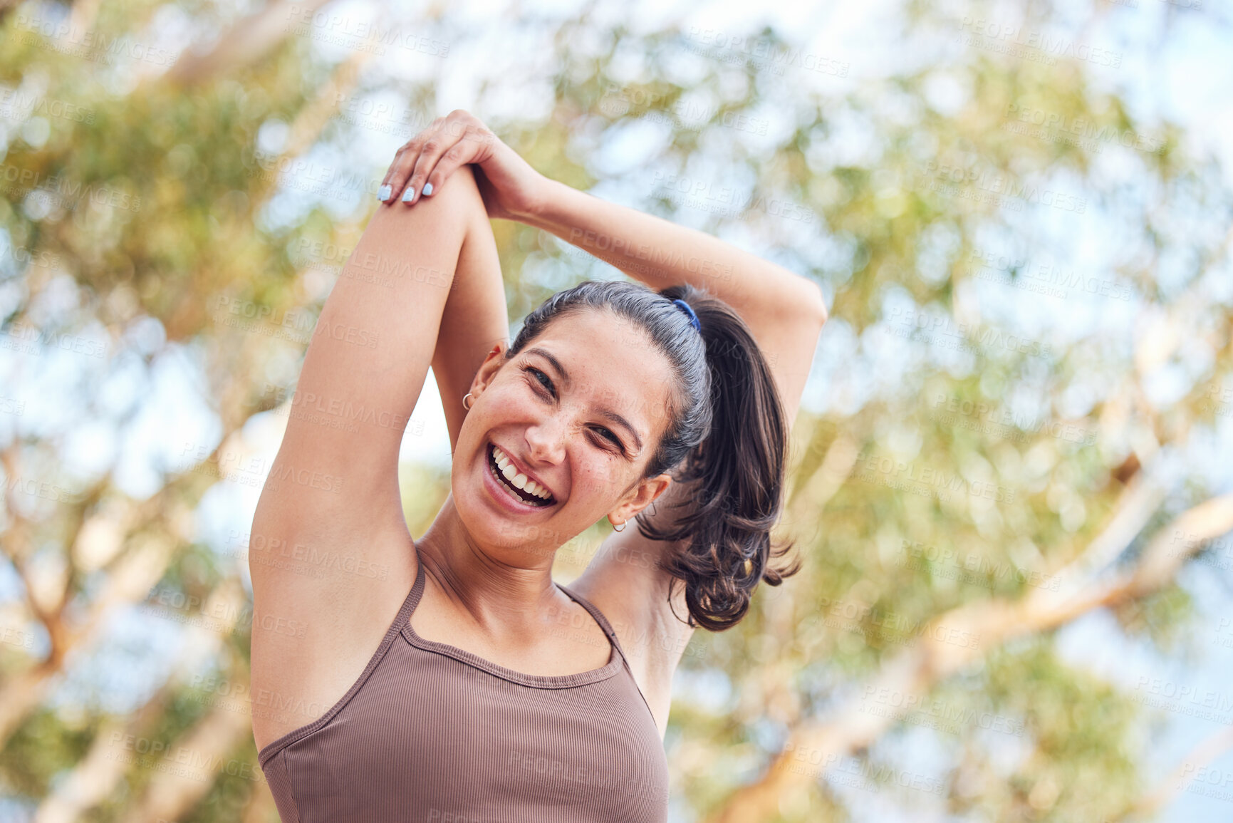 Buy stock photo Portrait of a sporty young woman stretching her arms while exercising outdoors