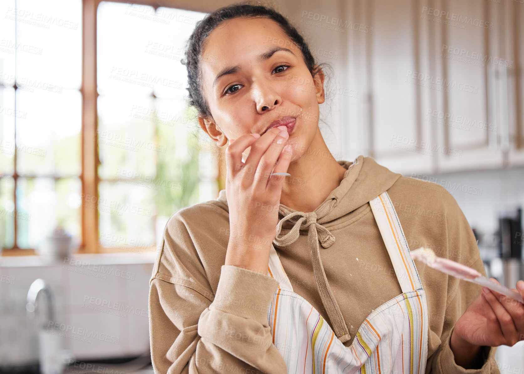 Buy stock photo Shot of a young woman tasting she made while baking