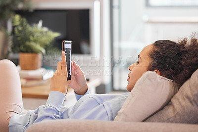 Buy stock photo Cropped shot of an attractive young woman texting while relaxing at home
