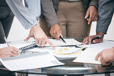 Buy stock photo Cropped shot of a group of unrecognizable white businesspeople looking over paperwork in the boardroom