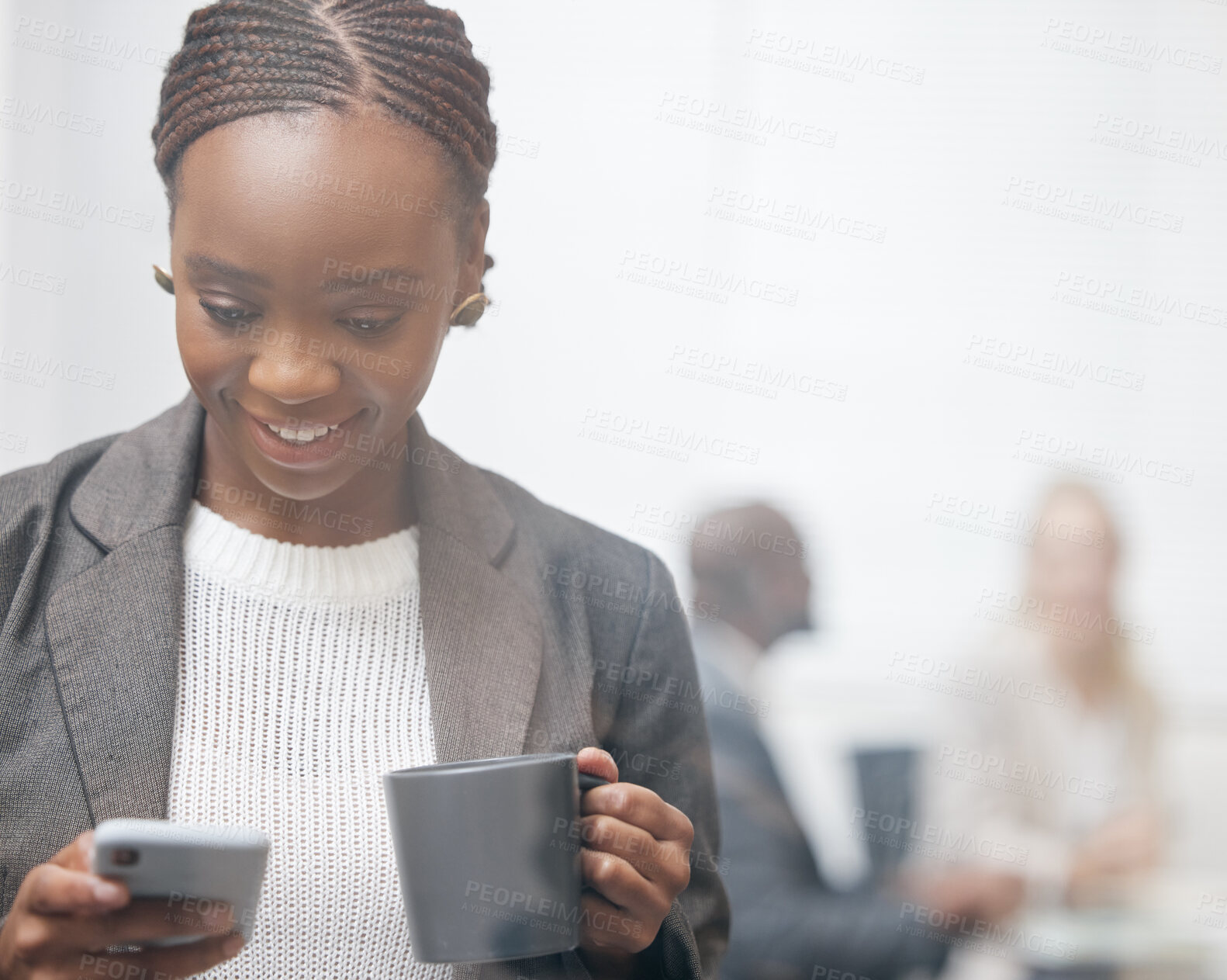 Buy stock photo Shot of a young businesswoman drinking coffee while using a cellphone in an office with her colleagues in the background