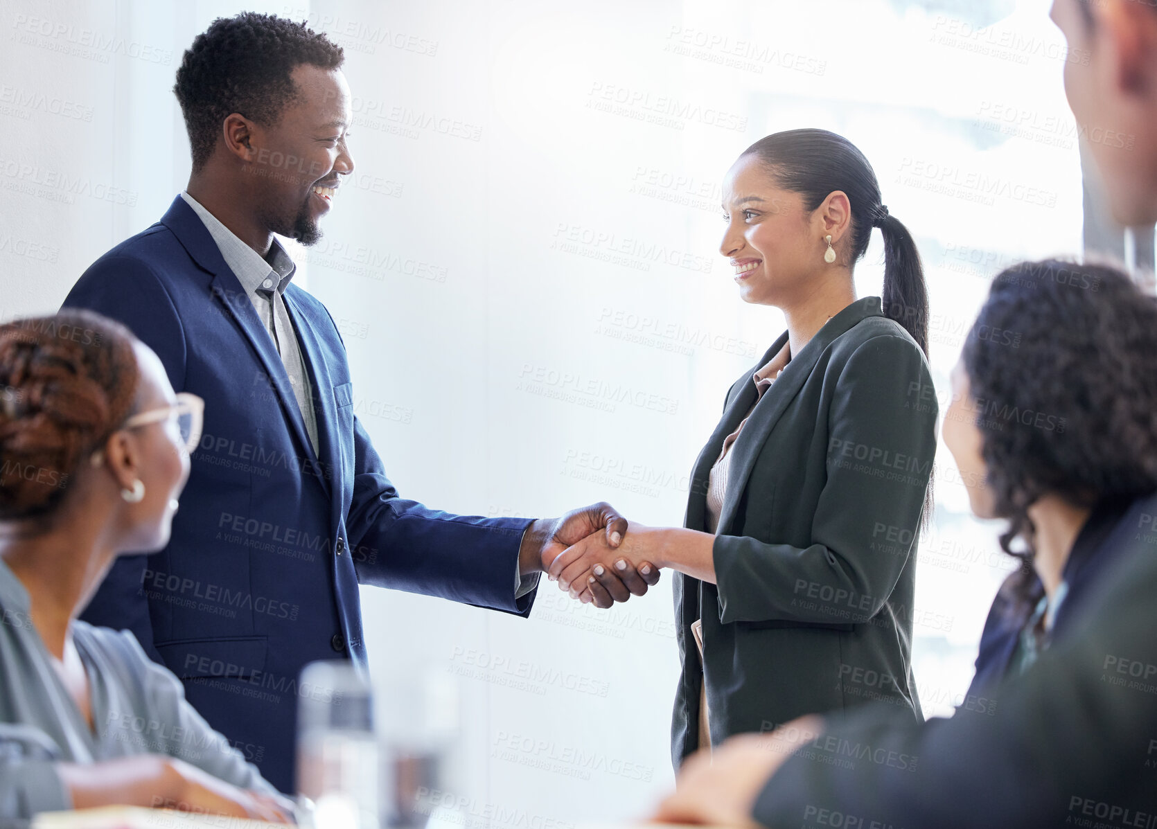 Buy stock photo Cropped shot of two white collar businesspeople shaking hands while standing in the boardroom during a meeting