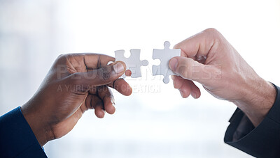Buy stock photo Cropped shot of two unrecognizable businesspeople completing a puzzle together in a modern office