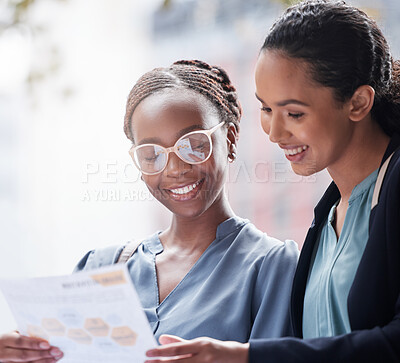 Buy stock photo Shot of two young businesswomen going through paperwork against a city background