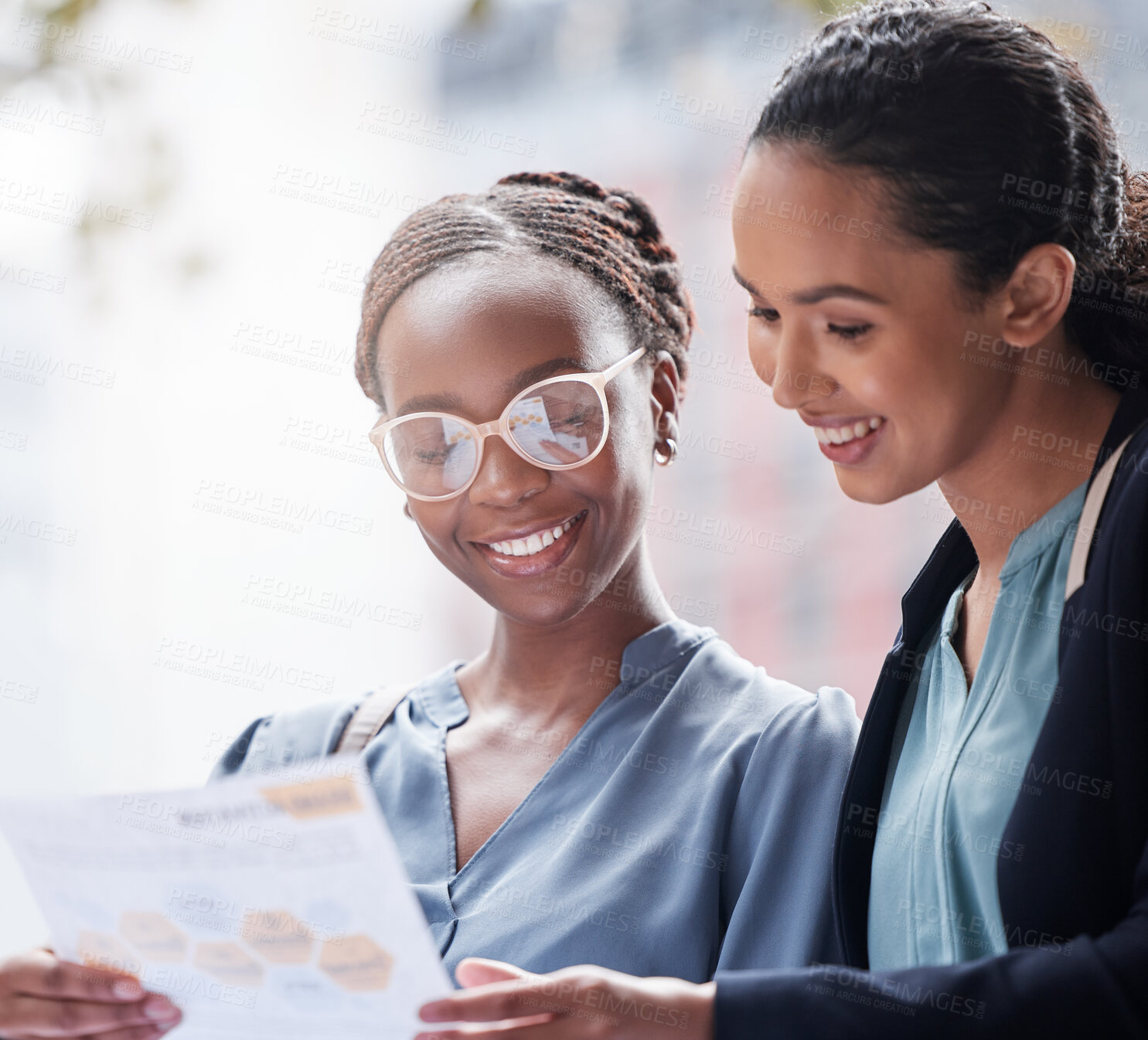 Buy stock photo Shot of two young businesswomen going through paperwork against a city background