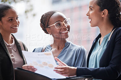 Buy stock photo Shot of a group of businesswomen going through paperwork against a city background