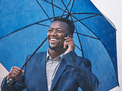 Buy stock photo Shot of a young businessman on call in the rain against a city background