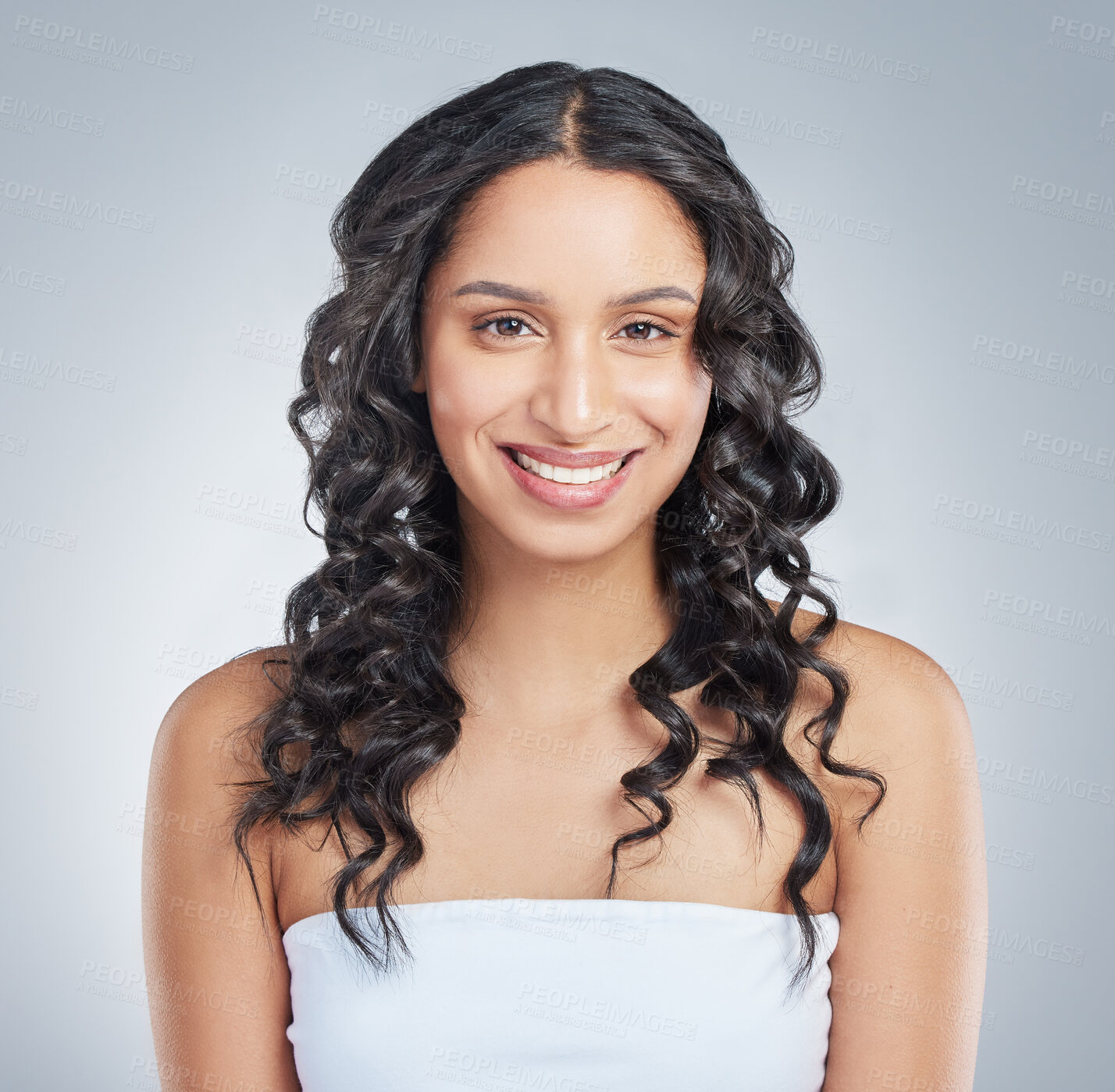 Buy stock photo Smile, portrait and woman in studio for curly hair treatment, wellness and shampoo, shine or cosmetics on grey background. Happy, face and model with beach waves, haircare and texture styling results