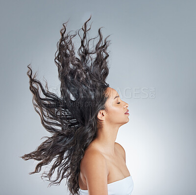 Buy stock photo Shot of an attractive young woman standing alone in the studio and flipping her hair
