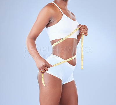 Buy stock photo Studio shot of a young woman measuring her waist
