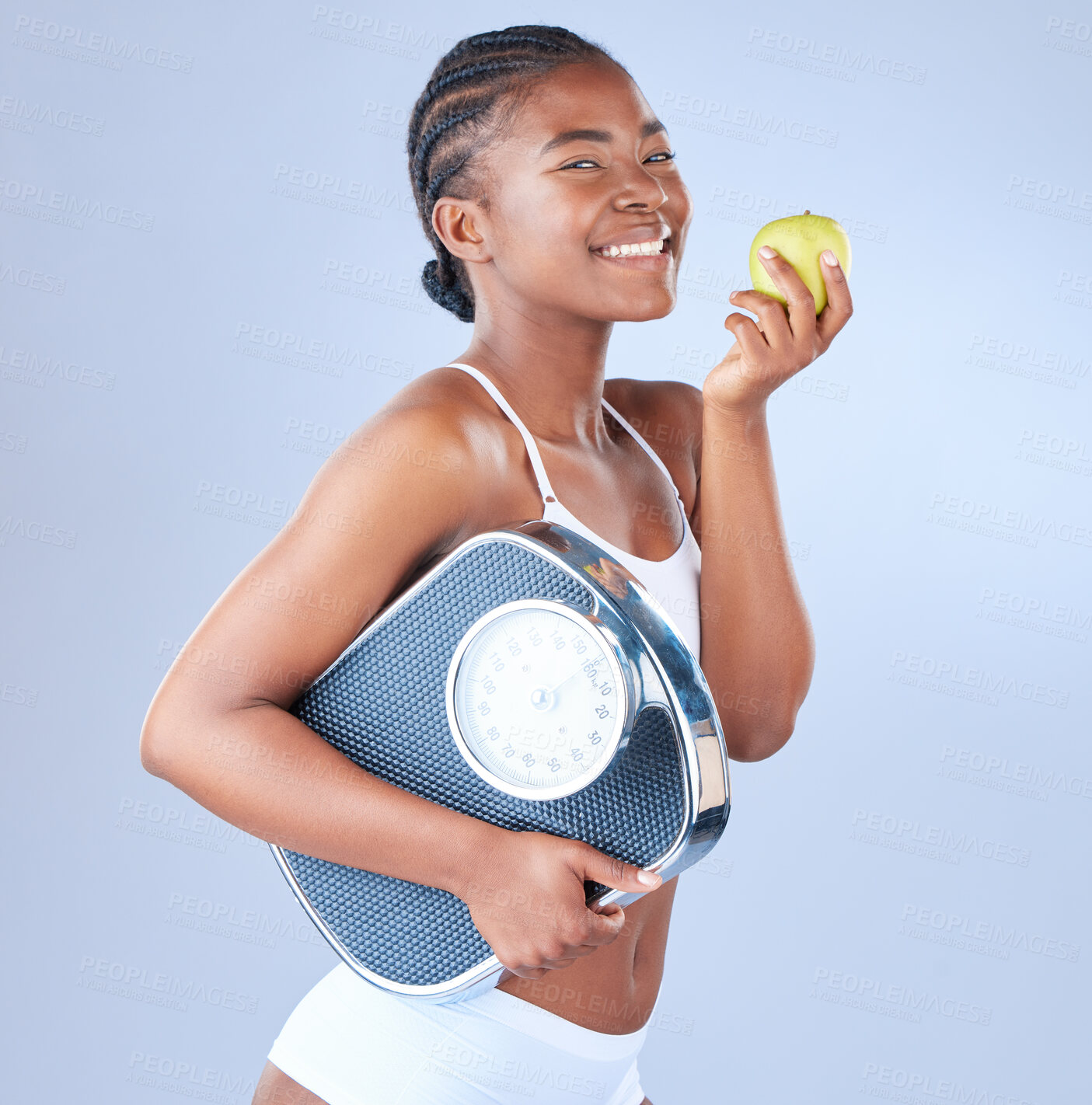 Buy stock photo Happy black woman, portrait and scale with apple for diet, nutrition or vitamins on a blue studio background. African, female person or model with natural green fruit for organic detox or weight loss