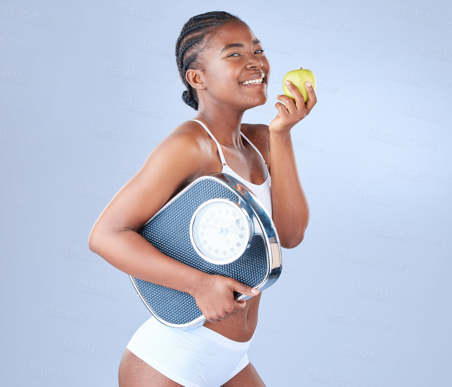 Buy stock photo Black woman, portrait and scale with apple for diet, nutrition or vitamins on a blue studio background. Happy African, female person or model with natural green fruit for organic detox or weight loss