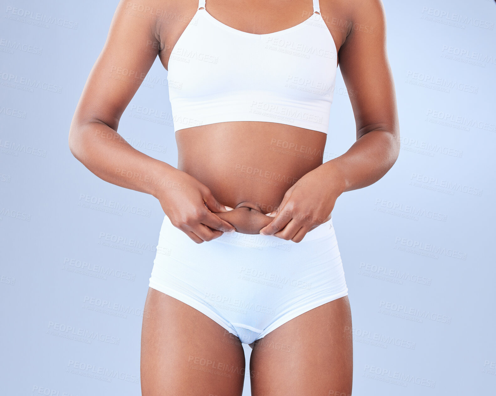 Buy stock photo Woman, body fat and lose weight with underwear for diet or nutrition on a blue studio background. Stomach or belly of female person or model touching skin in detox, liposuction or health and wellness