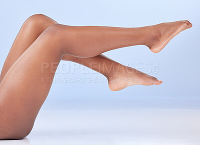 Buy stock photo Legs, floor and wellness for skin in studio with stretching, healthy body and natural glow by blue background. Woman, person and model with feet, hair removal and shine for cosmetic transformation