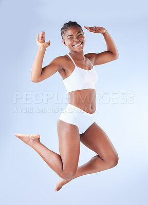 Buy stock photo Studio shot of a young woman jumping against a blue background