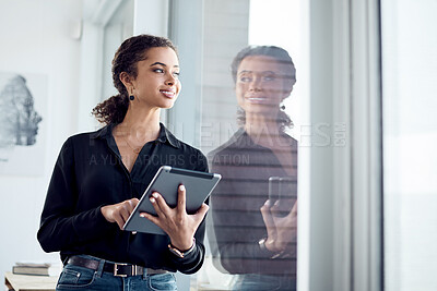 Buy stock photo Shot of a young businesswoman looking through a window while using a digital tablet in an office