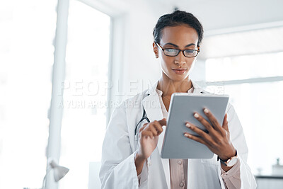 Buy stock photo Shot of a young female doctor using her digital tablet in her office