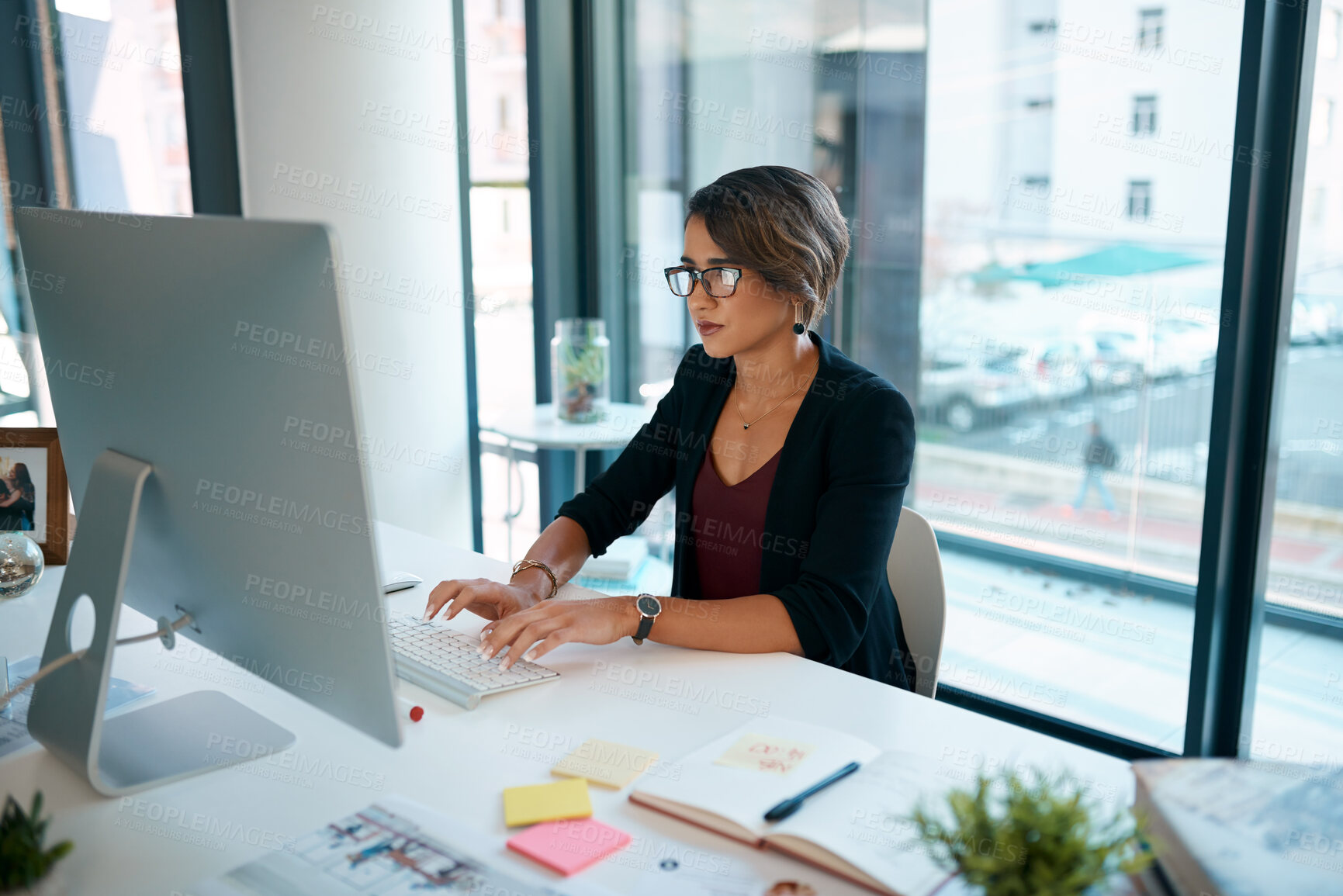 Buy stock photo Shot of an attractive young businesswoman sitting alone in the office and using her computer