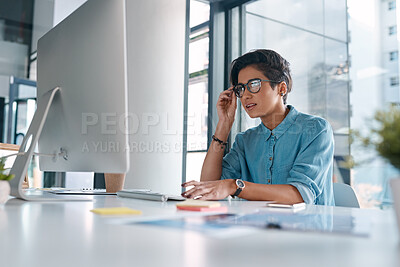 Buy stock photo Shot of an attractive young businesswoman sitting alone in the office and using her computer
