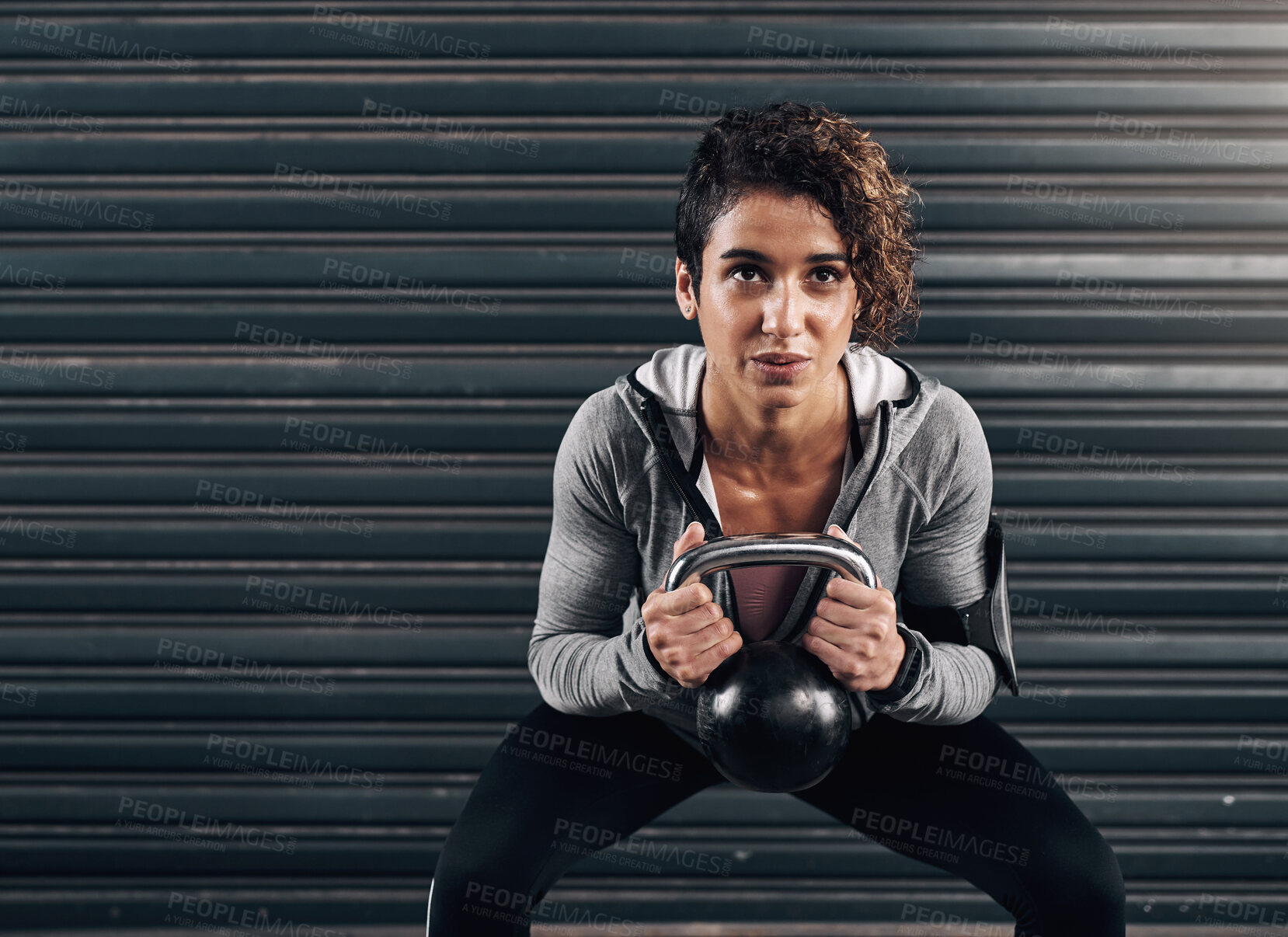 Buy stock photo Shot of a young fit woman using a kettle bell against a black background