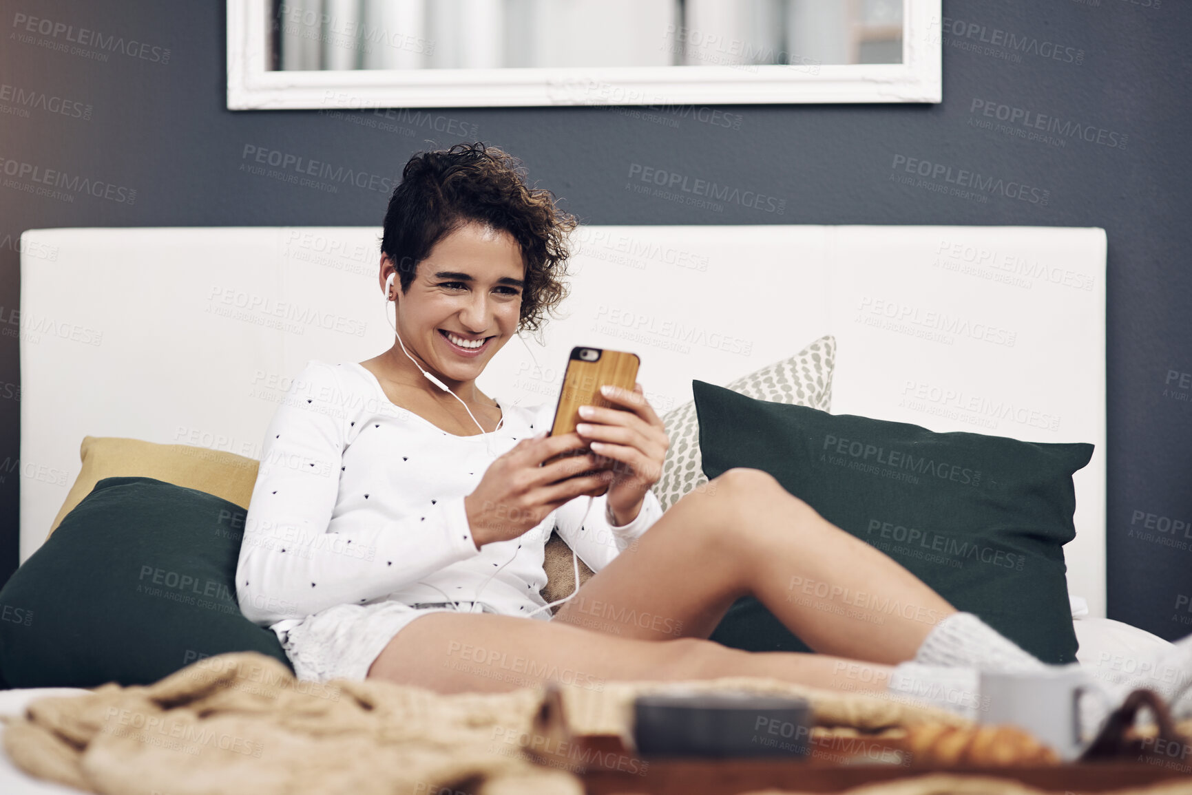Buy stock photo Bedroom, home and woman with cellphone, breakfast and smile with social media, digital app and audio. Apartment, bed and girl with smartphone, nutrition and connection with network, morning and sound