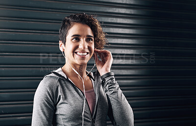 Buy stock photo Shot of a young woman choosing the perfect song for her run outside against a black background