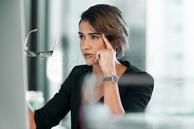 Buy stock photo Shot of an attractive young businesswoman sitting alone in the office and looking contemplative while using her computer