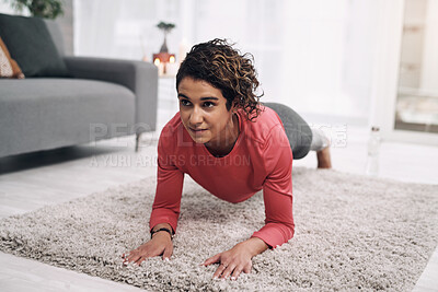 Buy stock photo Shot of a young woman in the plank position on the lounge floor at home