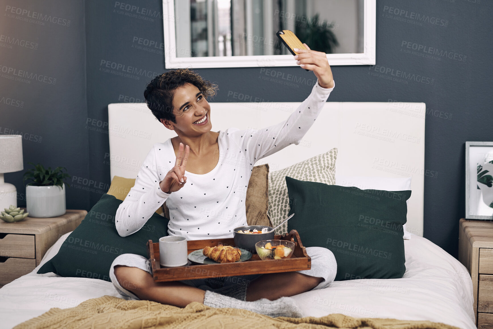 Buy stock photo Woman, selfie and hotel breakfast on bed as content creator or hospitality ambassador, eating or social media. Female person, cellphone and peace sign for morning for internet post, resort or travel