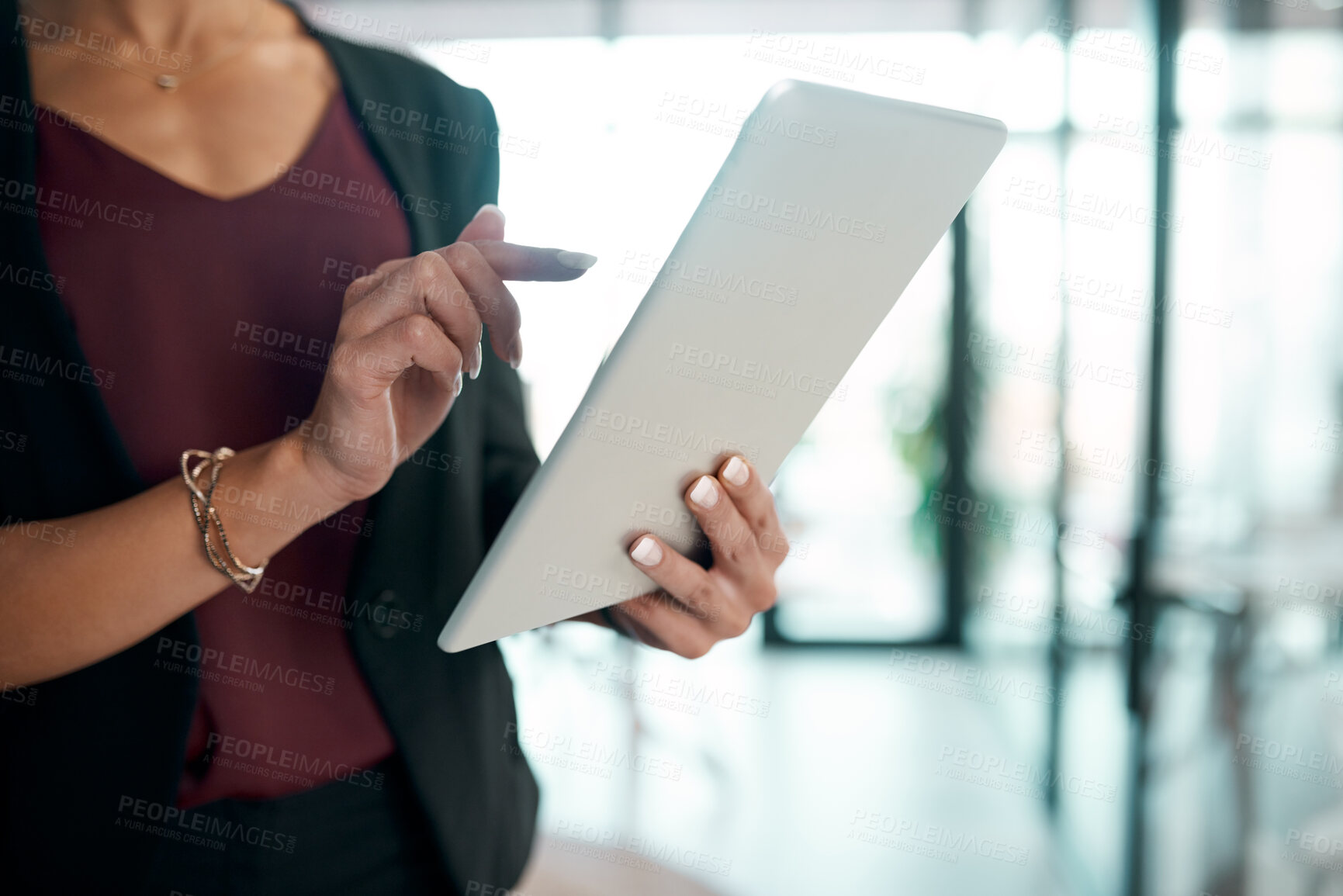 Buy stock photo Cropped shot of an unrecognisable businesswoman standing alone in the office and using a digital tablet