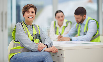 Buy stock photo Cropped portrait of an attractive young female construction worker sitting in the boardroom with her colleagues in the background