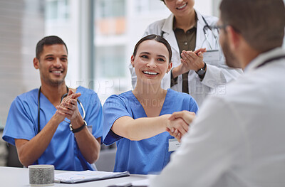 Buy stock photo Shot of a group of medical practitioners shaking hands and applauding during a meeting in a hospital boardroom