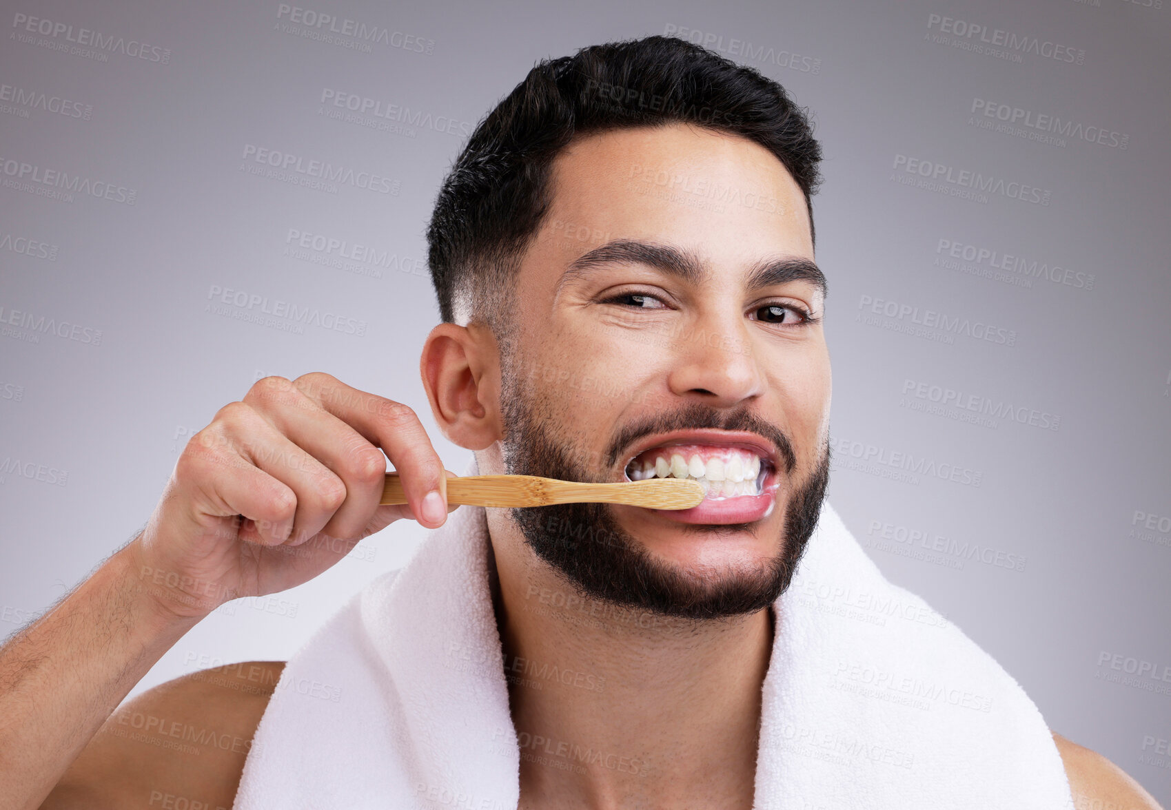 Buy stock photo Shot of a handsome young man brushing his teeth against a studio background