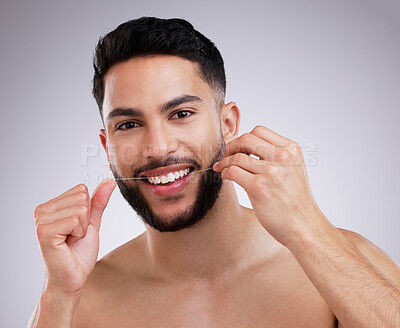 Buy stock photo Shot of a young man flossing his teeth against a studio background