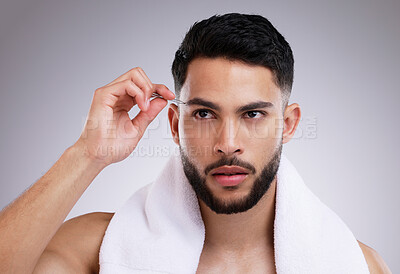 Buy stock photo Shot of a young man tweezing his eyebrows against a studio background