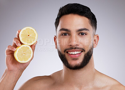 Buy stock photo Shot of a young man holding cut up lemons against a studio background