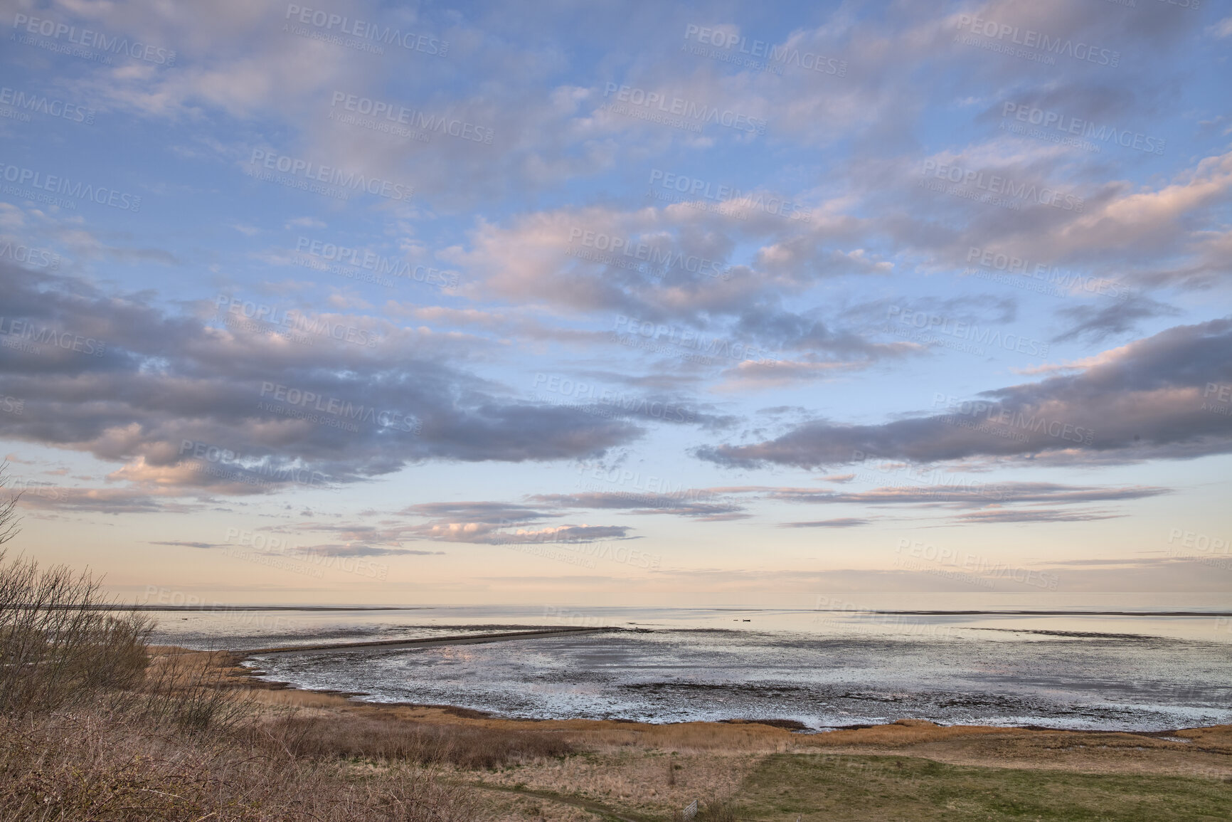 Buy stock photo A peaceful ocean or lake view at sunset with an overcast, cloudy sky background in winter. Landscape, banner and copyspace view of the beach while the sun sets by the countryside