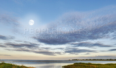 Buy stock photo Nature landscape of a cloudy blue sky over the ocean waters. Winter sunrise views on empty calm beach at low tide.  Beautiful seaside scene of the natural, peaceful and stressless outdoors.