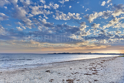 Buy stock photo Summer sunset views on empty calm beach at low tide.
Nature landscape of a coastline with a cloudy blue sky over the horizon. Seaside scene of tides and currents on a beautiful beach day