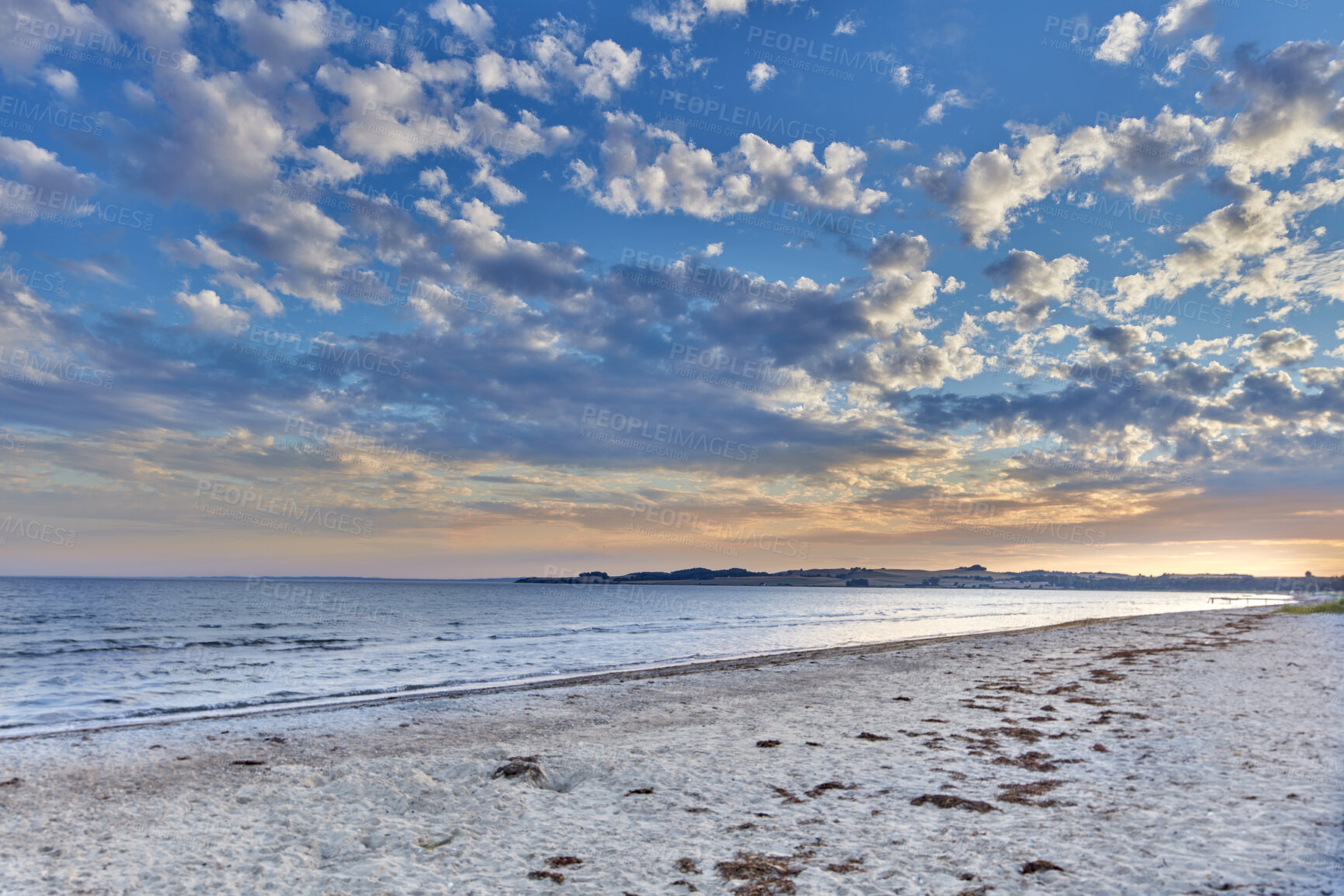 Buy stock photo Summer sunset views on empty calm beach at low tide.
Nature landscape of a coastline with a cloudy blue sky over the horizon. Seaside scene of tides and currents on a beautiful beach day