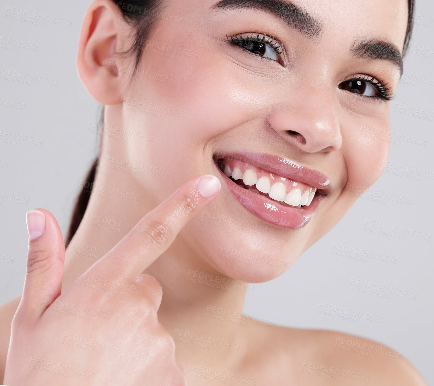 Buy stock photo Happy woman, portrait and pointing with teeth for dental care, hygiene or treatment on a gray studio background. Closeup of young female person with big smile for tooth whitening, lip gloss or glow