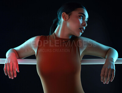 Buy stock photo Shot of an attractive young female ballerina practicing in a dark dance studio