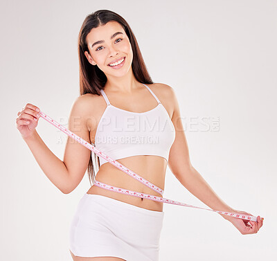 Buy stock photo Studio portrait of an attractive young woman using a measuring tape against a grey background
